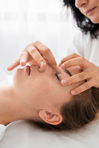 Female osteopathist treating a patient by massaging her face