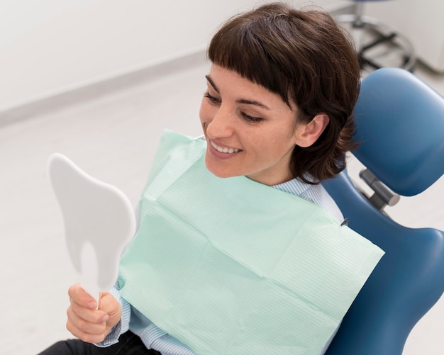 Female patient looking in the mirror after dental procedure