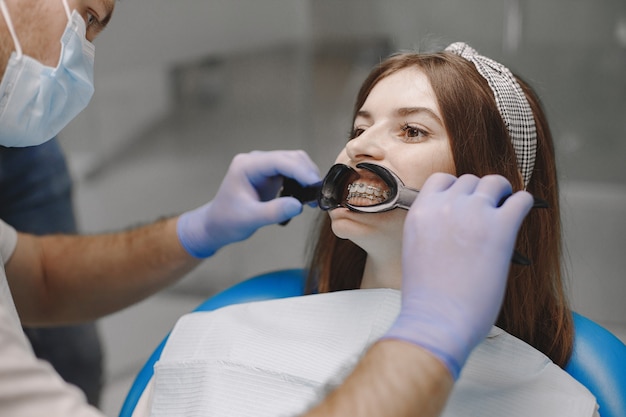 Female patient with braces has dental examination at dentist office. Woman wearing white clothes