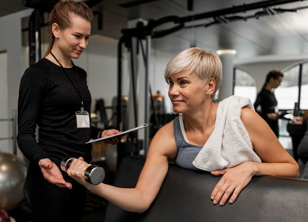 Free photo female personal trainer and her client using dumbbell