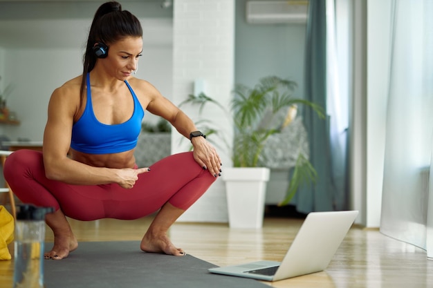 Female personal training using laptop while holding online class from home