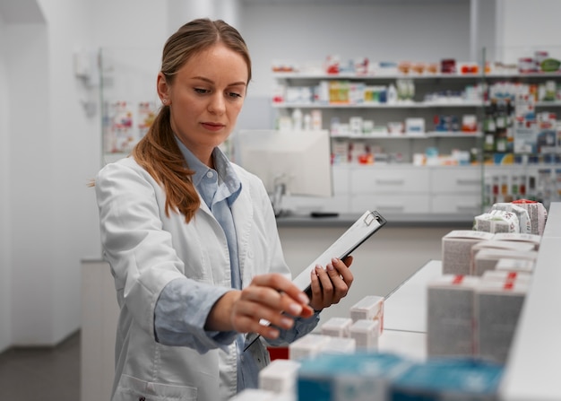 Female pharmacist checking medicine with clipboard