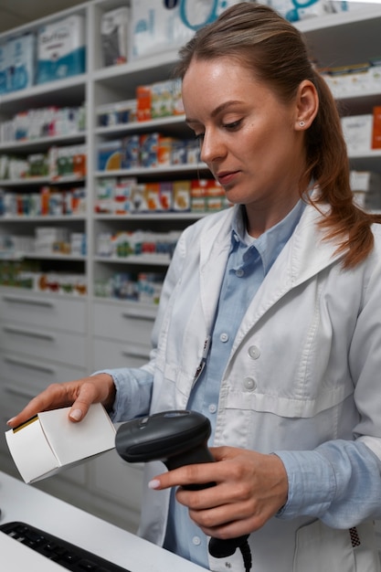 Free photo female pharmacist scanning medicine at the counter