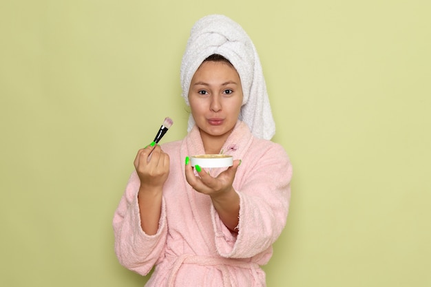 female in pink bathrobe doing make-up