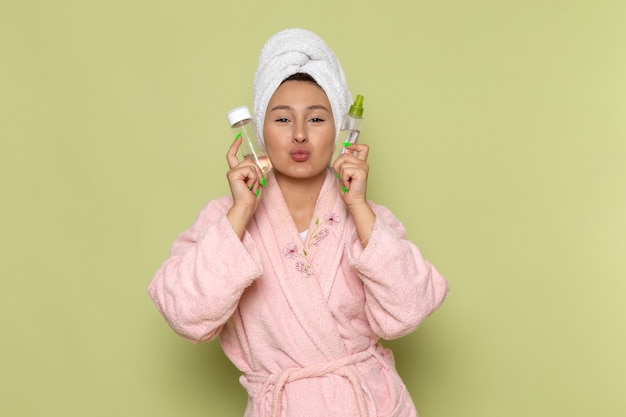 female in pink bathrobe holding spray flasks