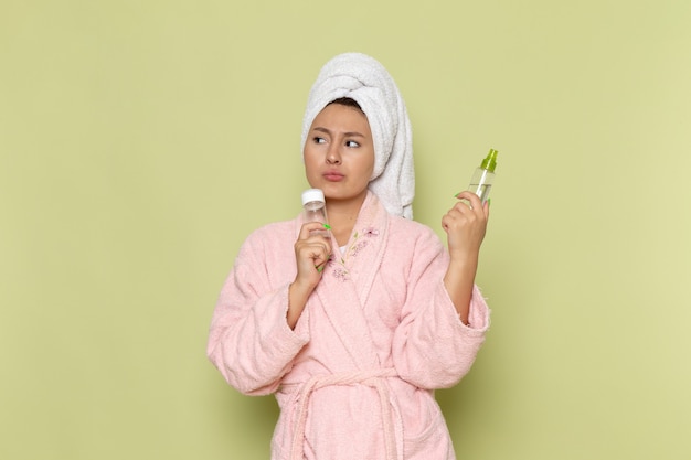 Free Photo female in pink bathrobe holding spray flasks