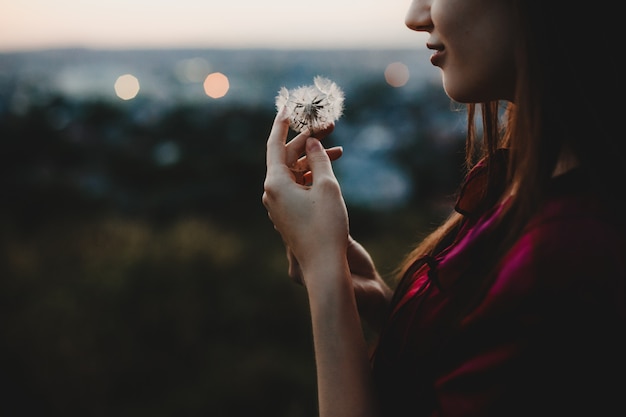 Free photo female portrait. nature. pretty woman plays with dandelion stand