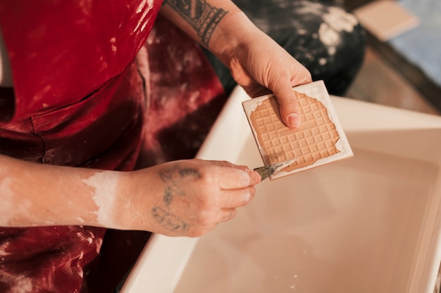 Free photo female potter removing the paint with sharp tools over the tub