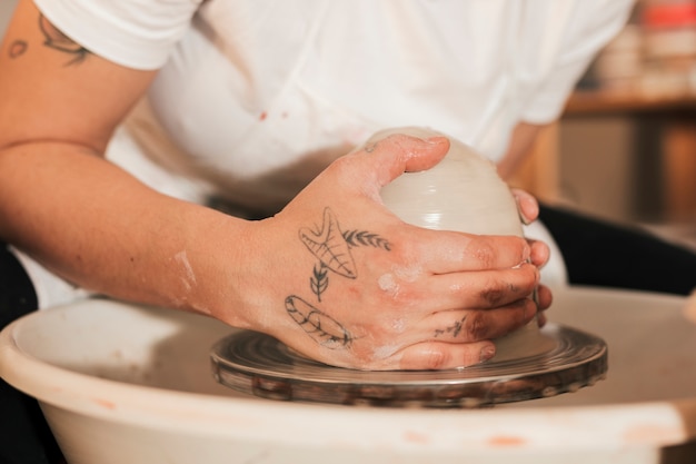 Female potter's hands close-up with clay on pottery wheel