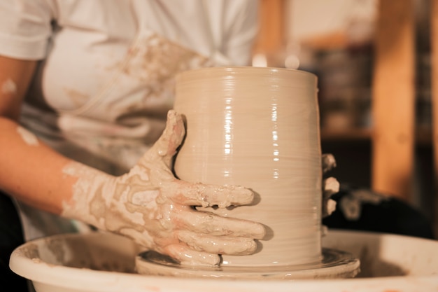 Female potter shaping pot in pottery workshop