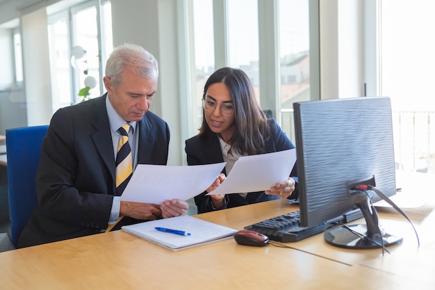 Free photo female professional explaining document details to client at workplace. serious business leader consulting financial or legal expert. teamwork or cooperation concept