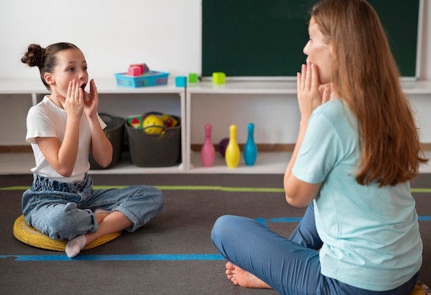 Free photo female psychologist helping a girl in speech therapy