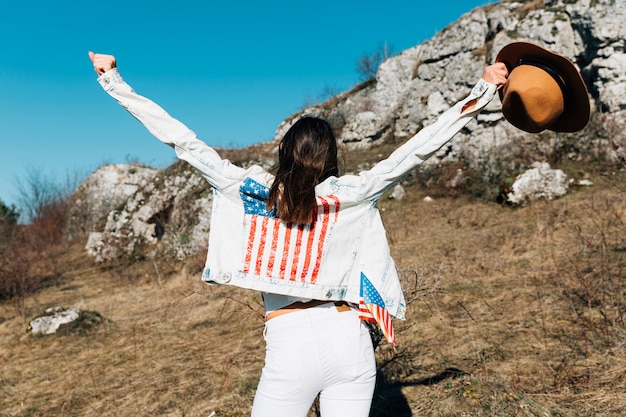 Free photo female raising hands with hat in nature