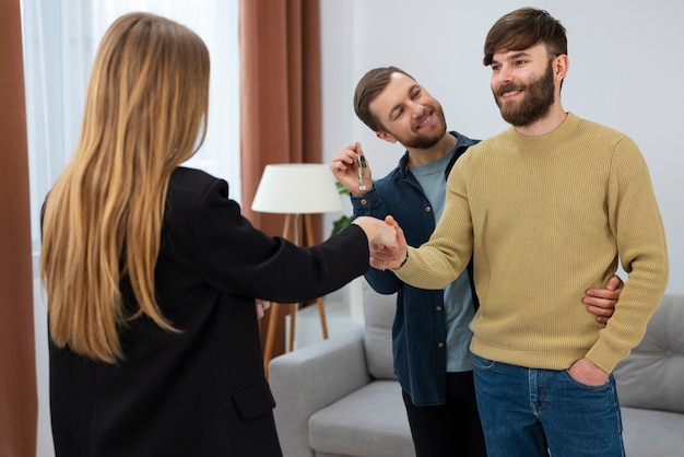 Free photo female real estate agent talking business and showing house to gay couple