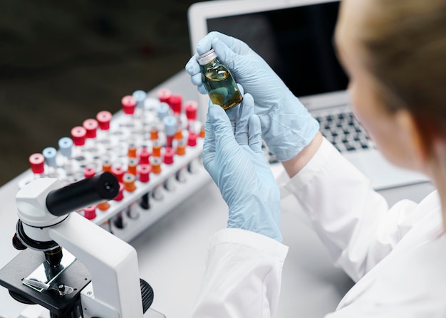 Free photo female researcher in the laboratory with test tubes and vaccine bottle