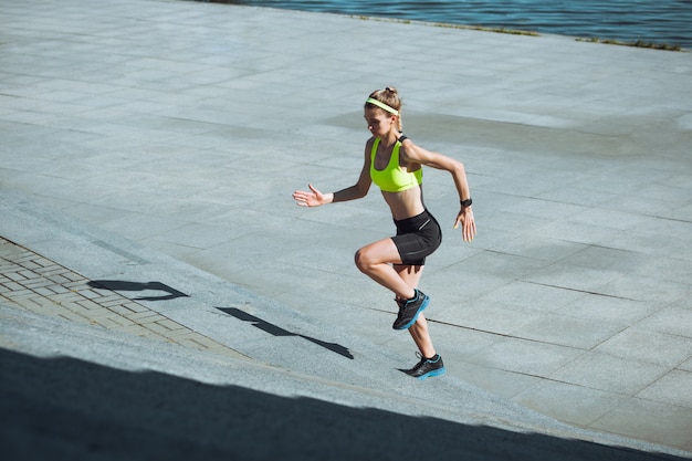 Free photo female runner, athlete training outdoors in summer's sunny day.