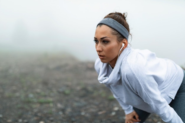 Free Photo female runner catching her breath and taking a break after jogging in nature on foggy weather copy space