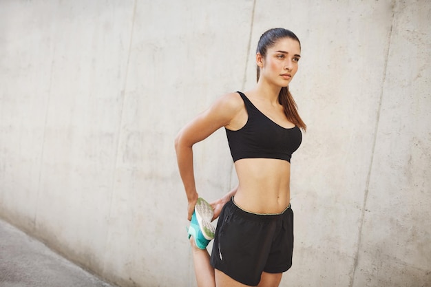 Female running athlete stretching on her way to perfect body shape Urban sport concept