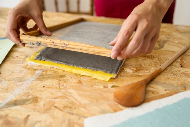 Female's hand placing mold over paper pulp