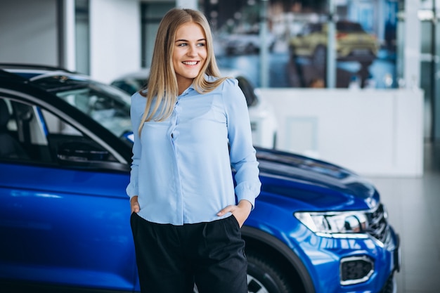 Free photo female salesperson at a car showroom by the car