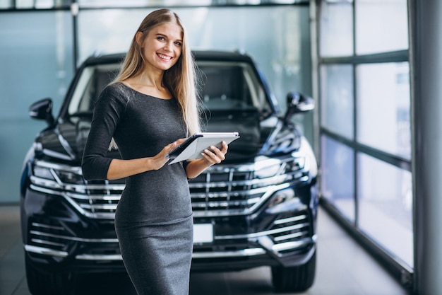 Free photo female salesperson at a car showroom by the car