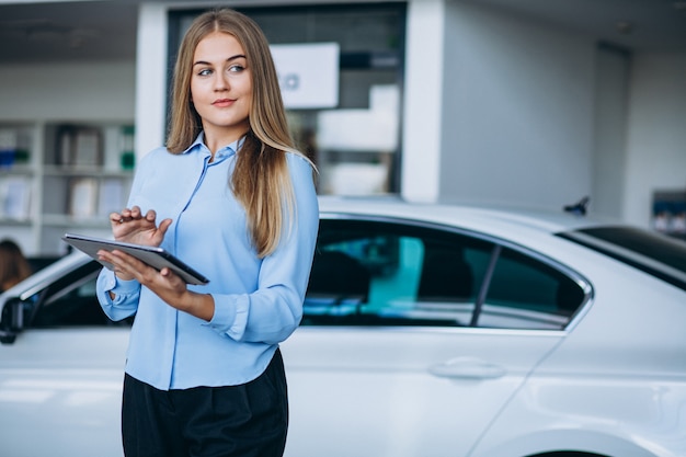 Free photo female salesperson at a car showroom by the car