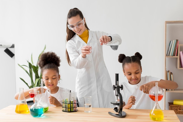 Female scientist teaching young girls chemistry experiments