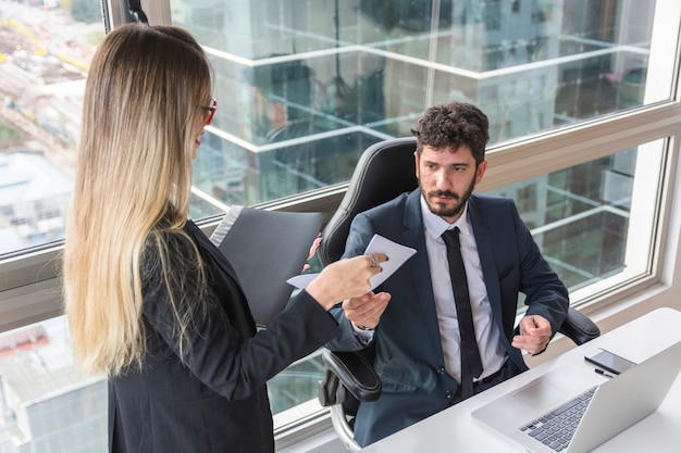 Female secretary giving document to male manager at workplace