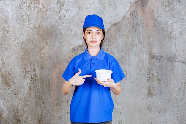 Free Photo female service agent in blue uniform holding a plastic bowl