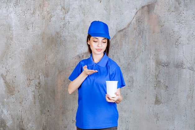 Free photo female service agent in blue uniform holding a white disposable cup.