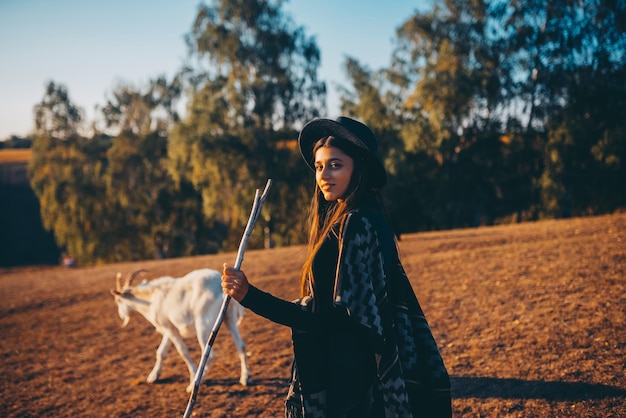 A female shepherd grazes goats on a meadow