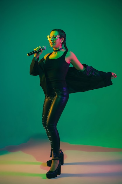 Female singer portrait isolated on green studio wall in neon light