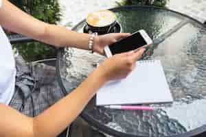 Free photo female sitting at outdoor cafe using cellphone