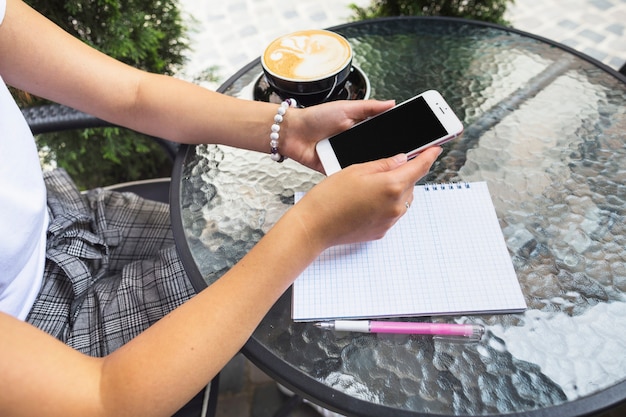 Female sitting at outdoor cafe using cellphone