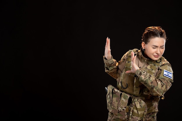 Female soldier in camouflage on black wall