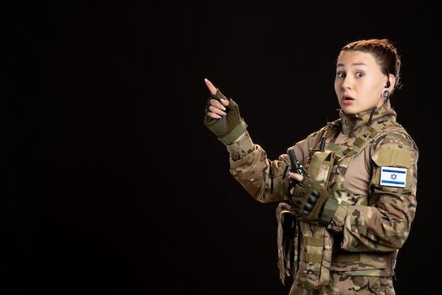 Female soldier in camouflage with grenade on the black wall