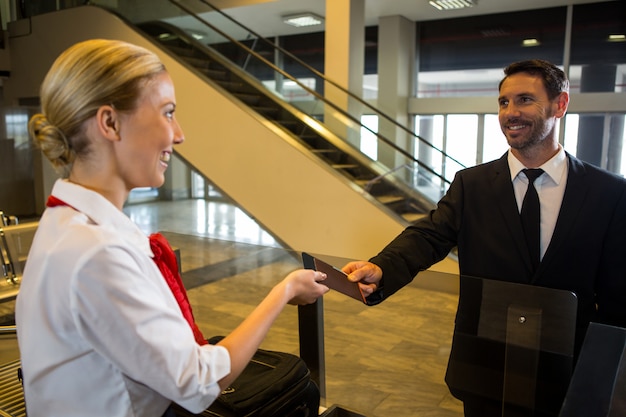 Female staff giving boarding pass to the passenger