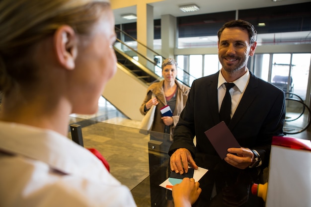 Free photo female staff giving boarding pass to the passenger