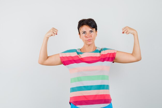 Female in striped t-shirt showing muscles of arms and looking confident , front view.