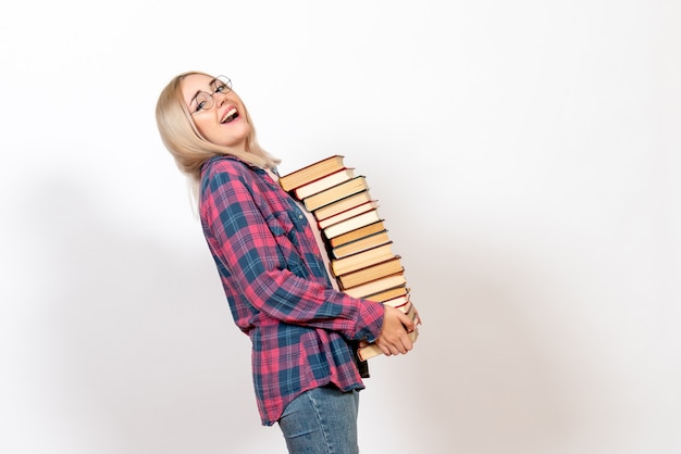 Free Photo female student holding different heavy books on white