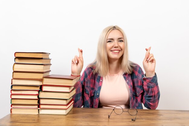 female student just sitting with books crossing her fingers on white