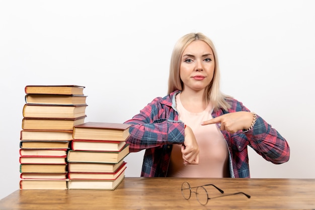 Free photo female student just sitting with books pointing at her wrist on white