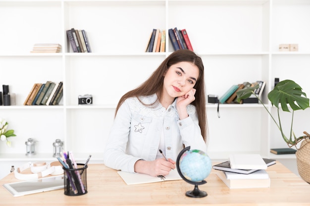 Female student sitting holding pen and thinking