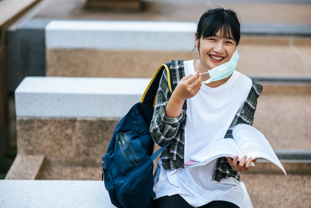 Female student sitting on the stairs and read a book.