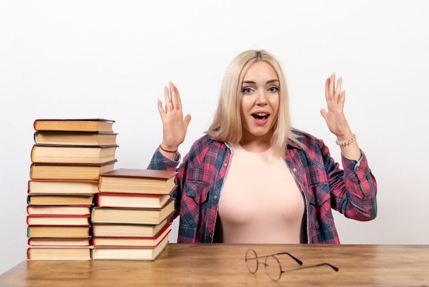 female student sitting with books and posing on white