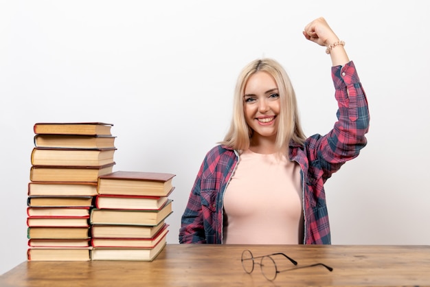 female student sitting with books and posing on white