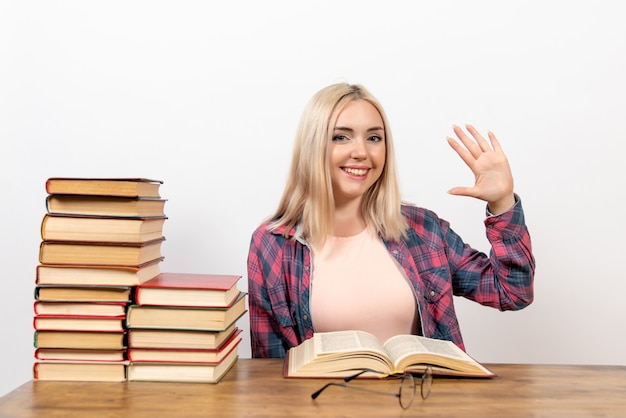 Free photo female student sitting with books and reading on white