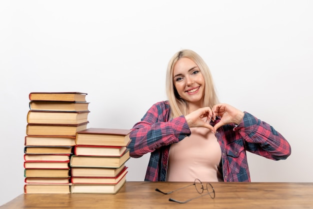 Free Photo female student sitting with different books smiling on white