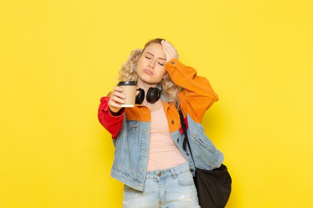 female student young in modern clothes holding coffee on yellow