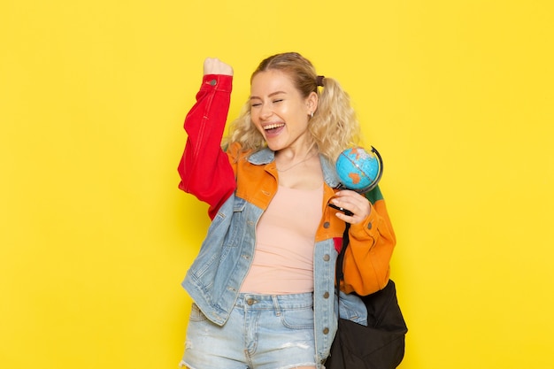 female student young in modern clothes holding little globe with happy face on yellow